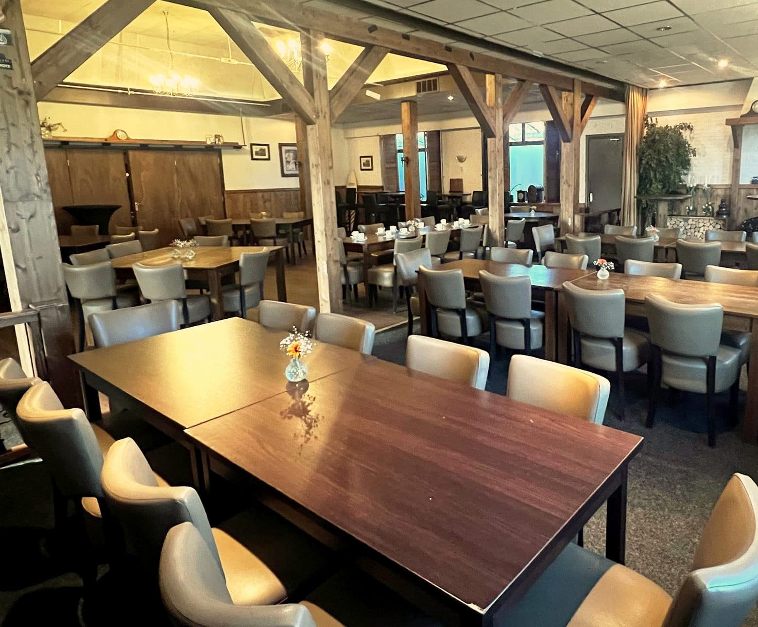 De grote zaal van Coens Tapperij met houten spanten en gedekte tafels