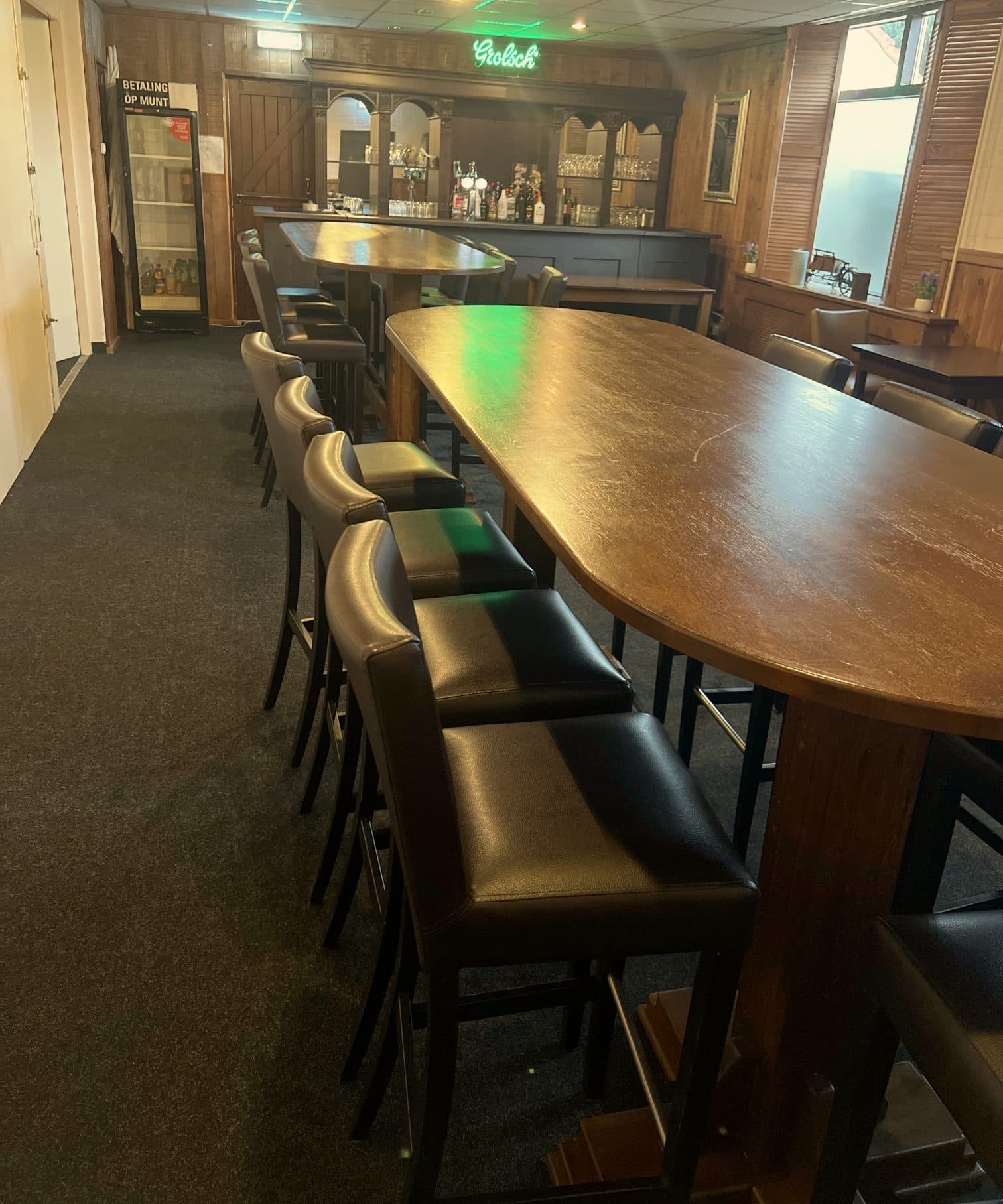 De kleine zaal met eigen bar en een lange tafel met barkrukken